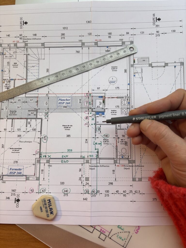vue rapprochée et plongeante sur un plan de maison avec une main tenant un crayon, illustrant Juliette décoratrice d'intérieur la Roche sur Yon travaillant
