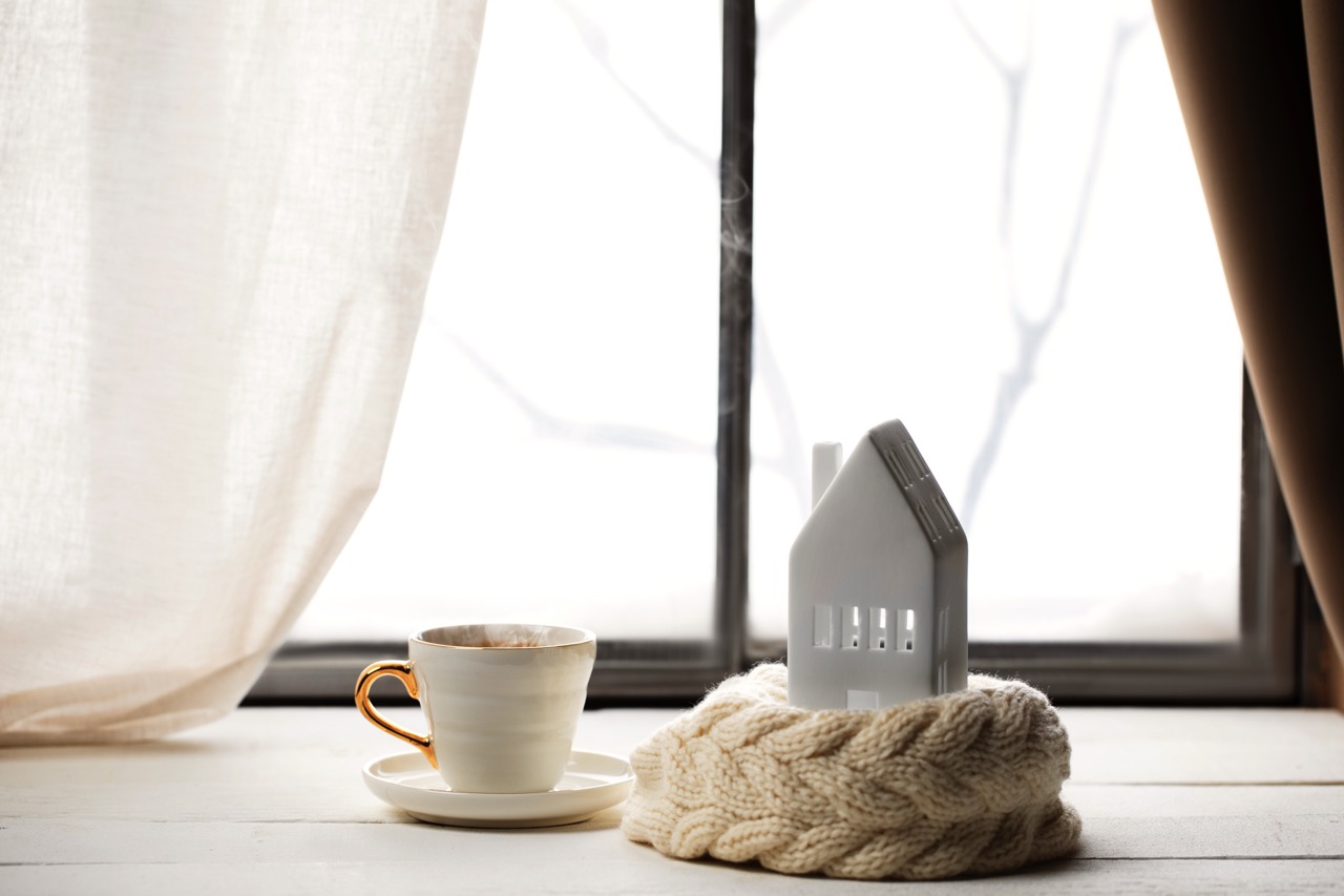 Ambiance douce, rideau, tasse et maison miniature en céramique. Illustre le changement de l'intérieur à venir.