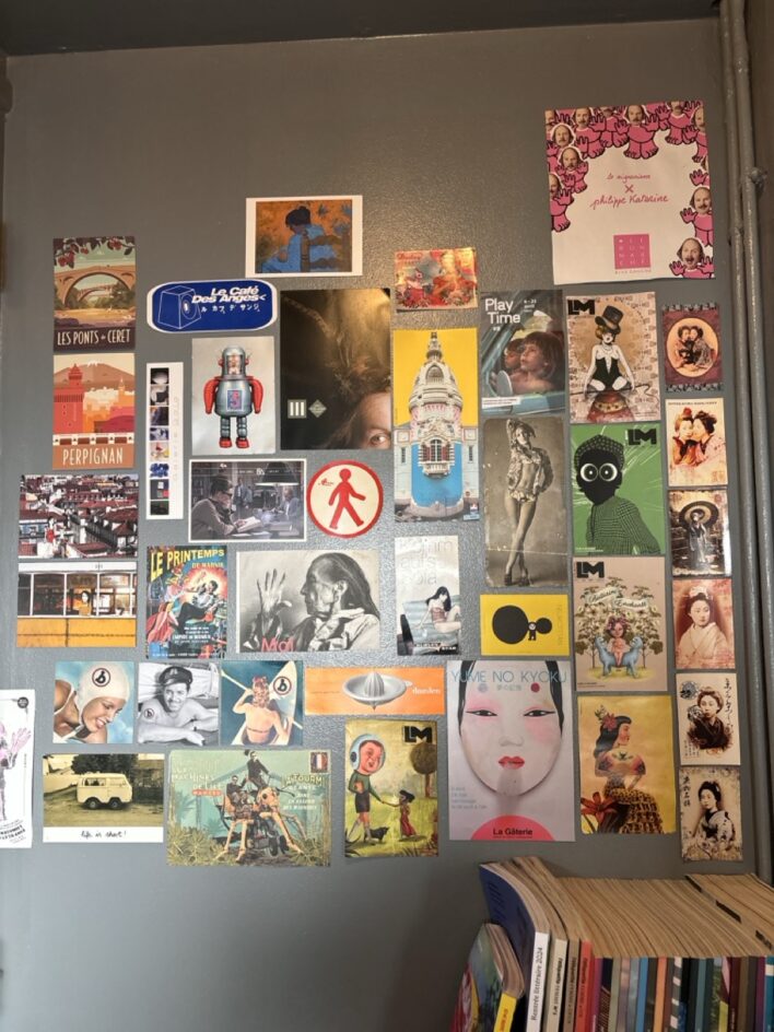 Mur recouvert de cartes postales, illustrations rétro et collages graphiques colorés.
